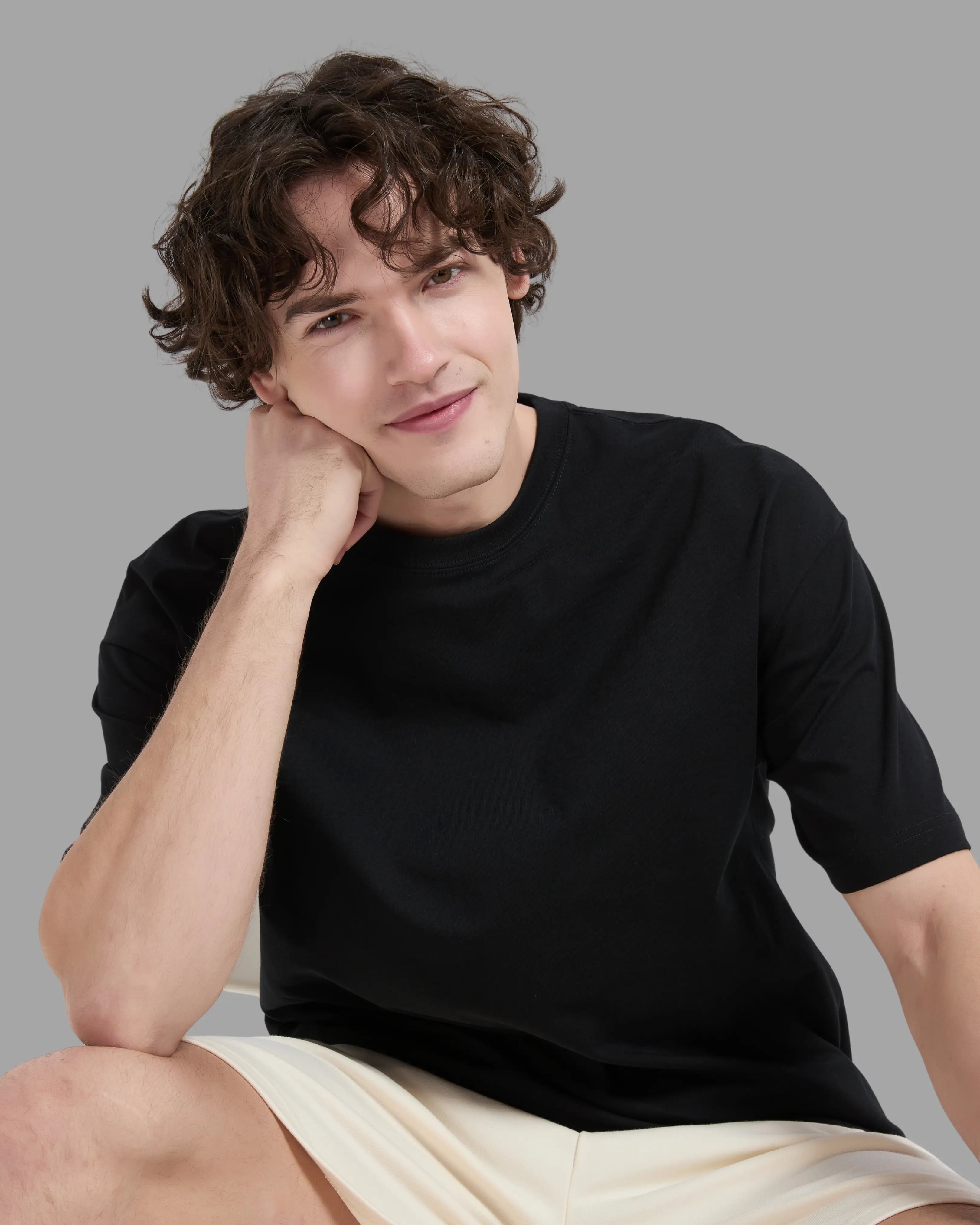man wearing black t-shirt with oversized drop shoulder design, heavyweight 100% cotton fabric